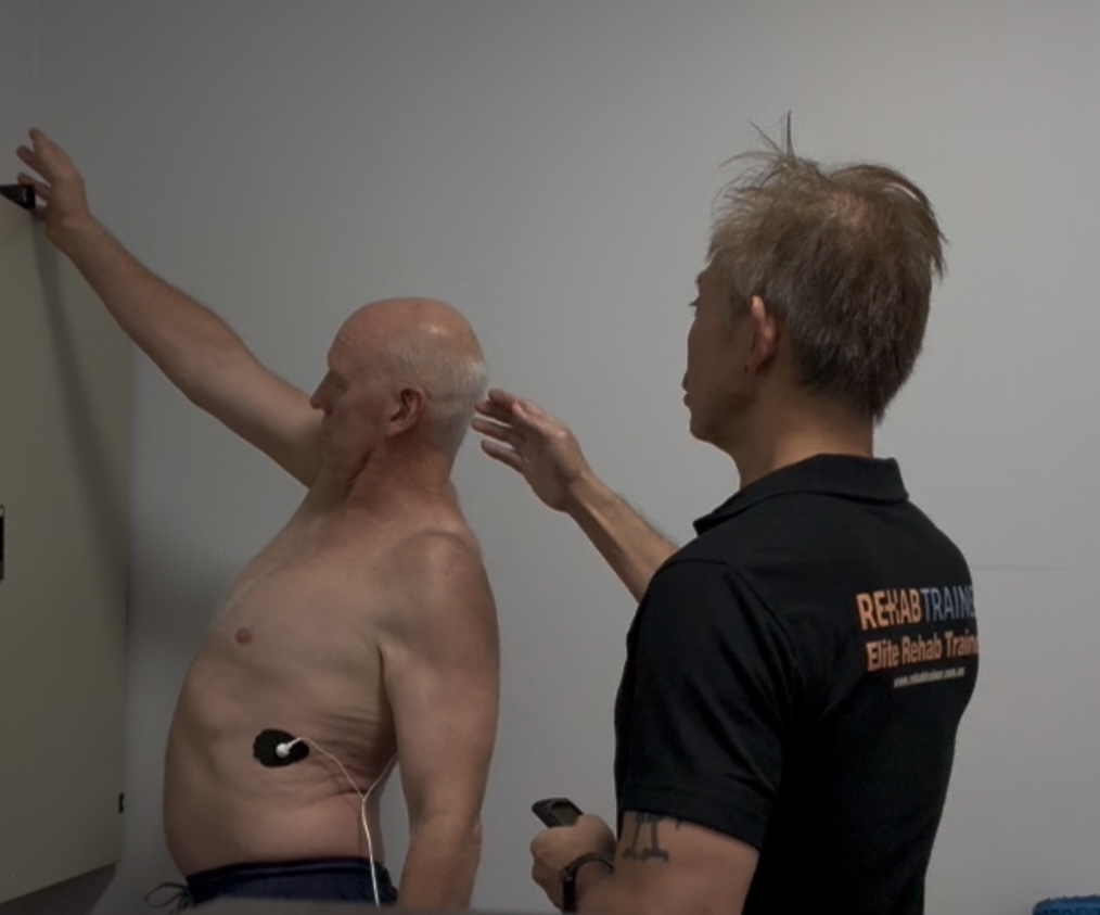 Calvin assisting a client with shoulder rehabilitation work
